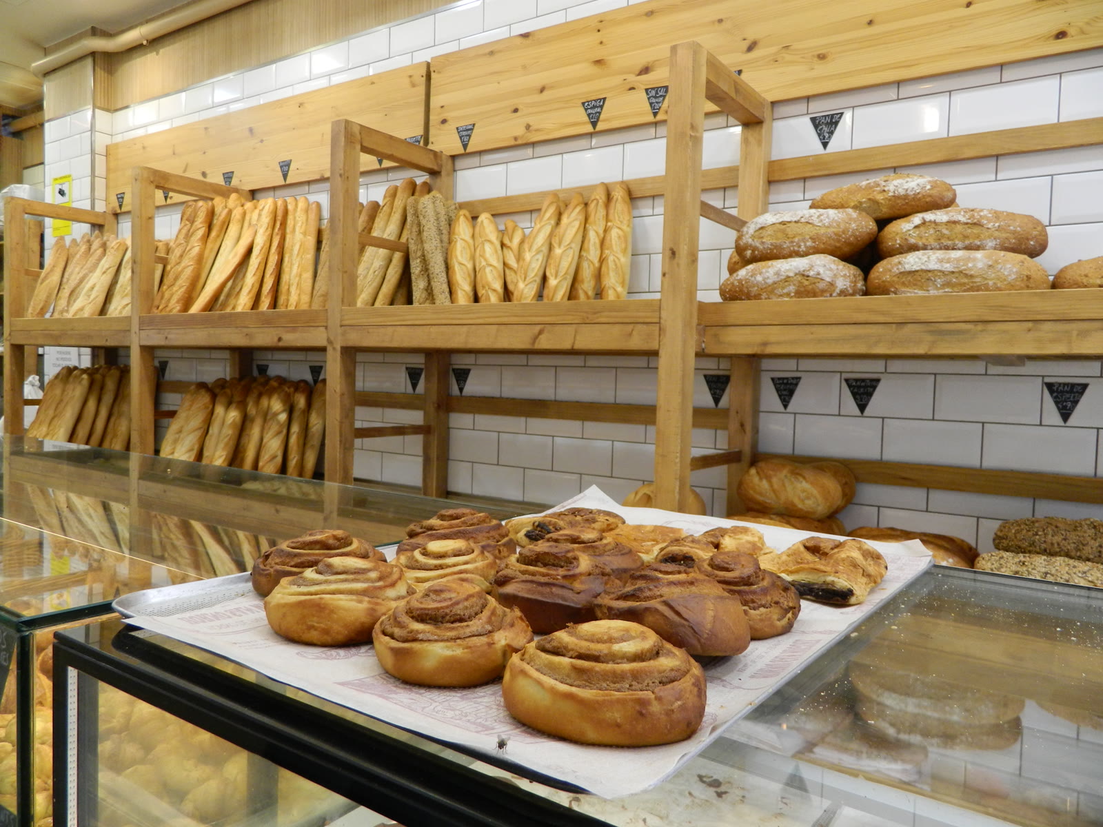 Estanterías de pan artesanal, baguettes y hogazas recién horneadas en Horno San Miguel